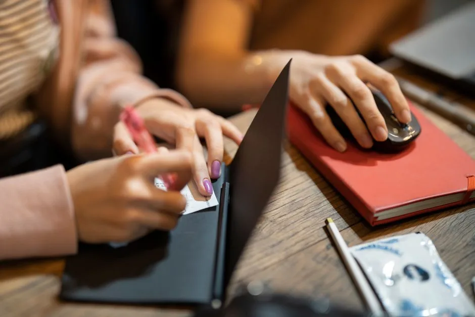 Person comparing notes beside a computer at a desk