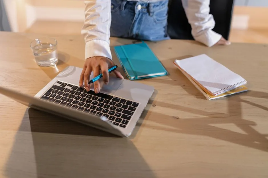Person seated at a desk with a computer and notebook